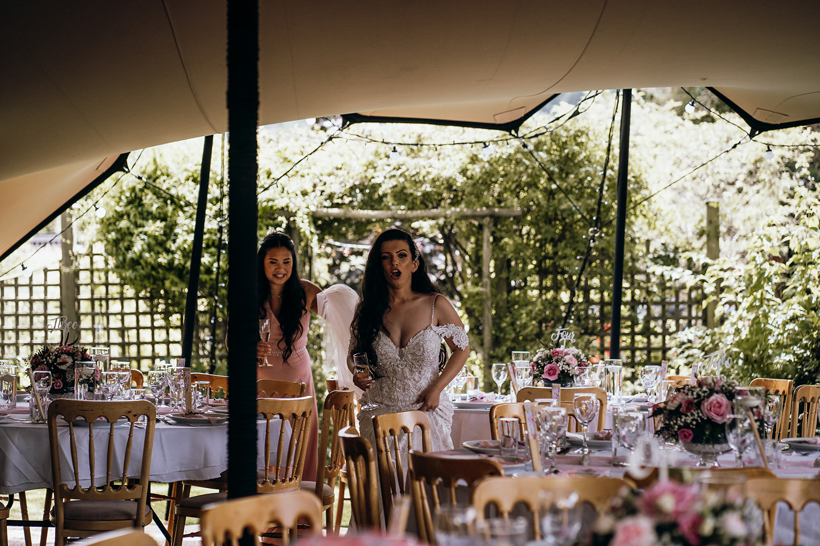 Bride and bridesmaid entering the reception under the stretch tent