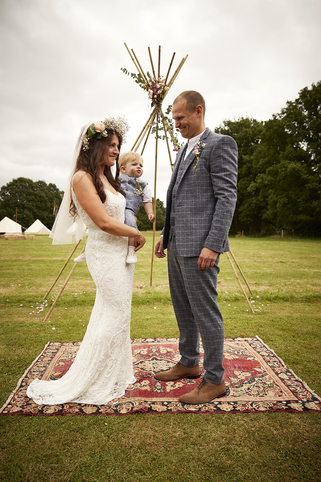 Bride and groom with bell tents in the distance