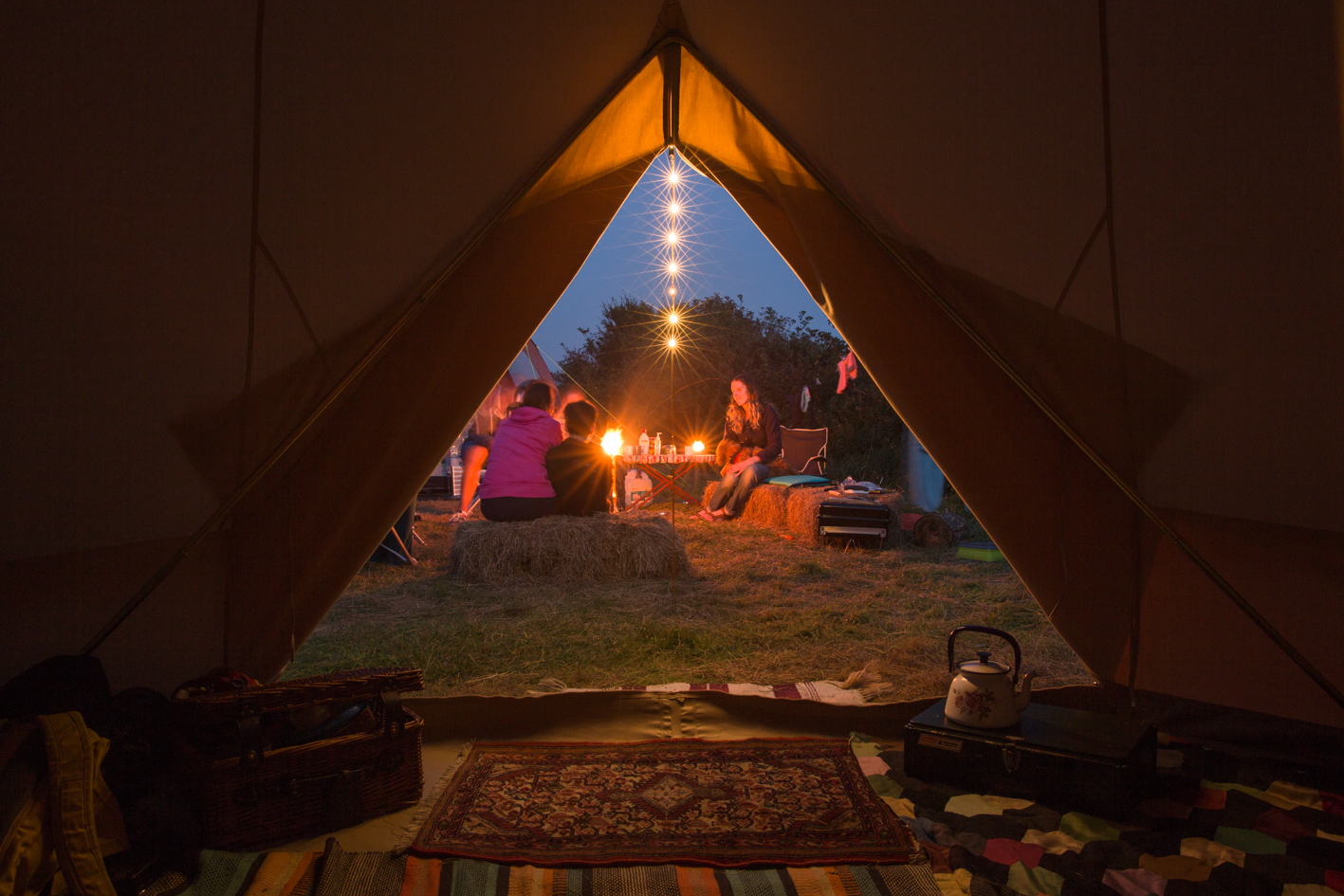 Bell tent at night with lights and friends