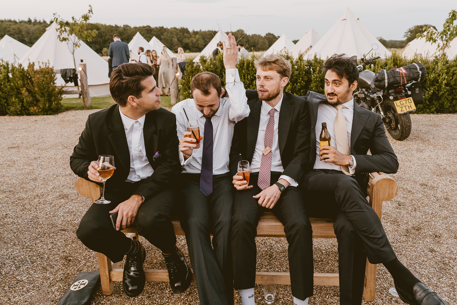Groomsmen relaxing on a bench by the bell tents