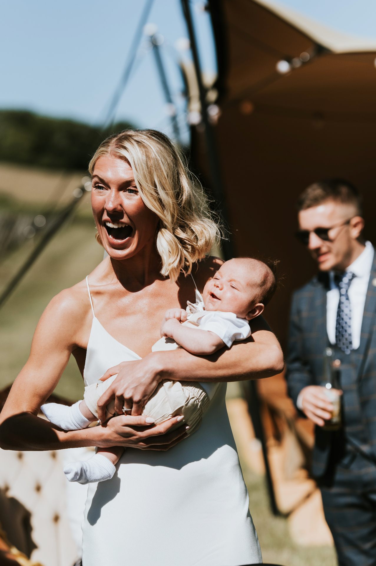 Guest laughing with a baby outside the stretch tent